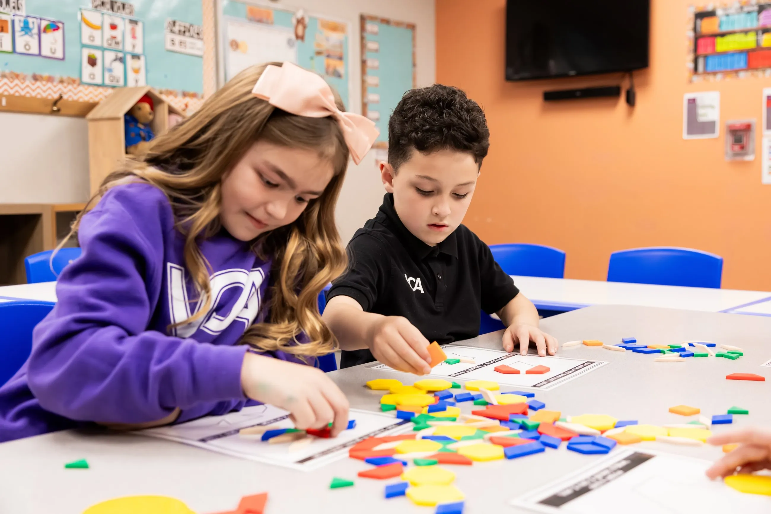 Two students sort colorful pattern blocks together at a classroom table.