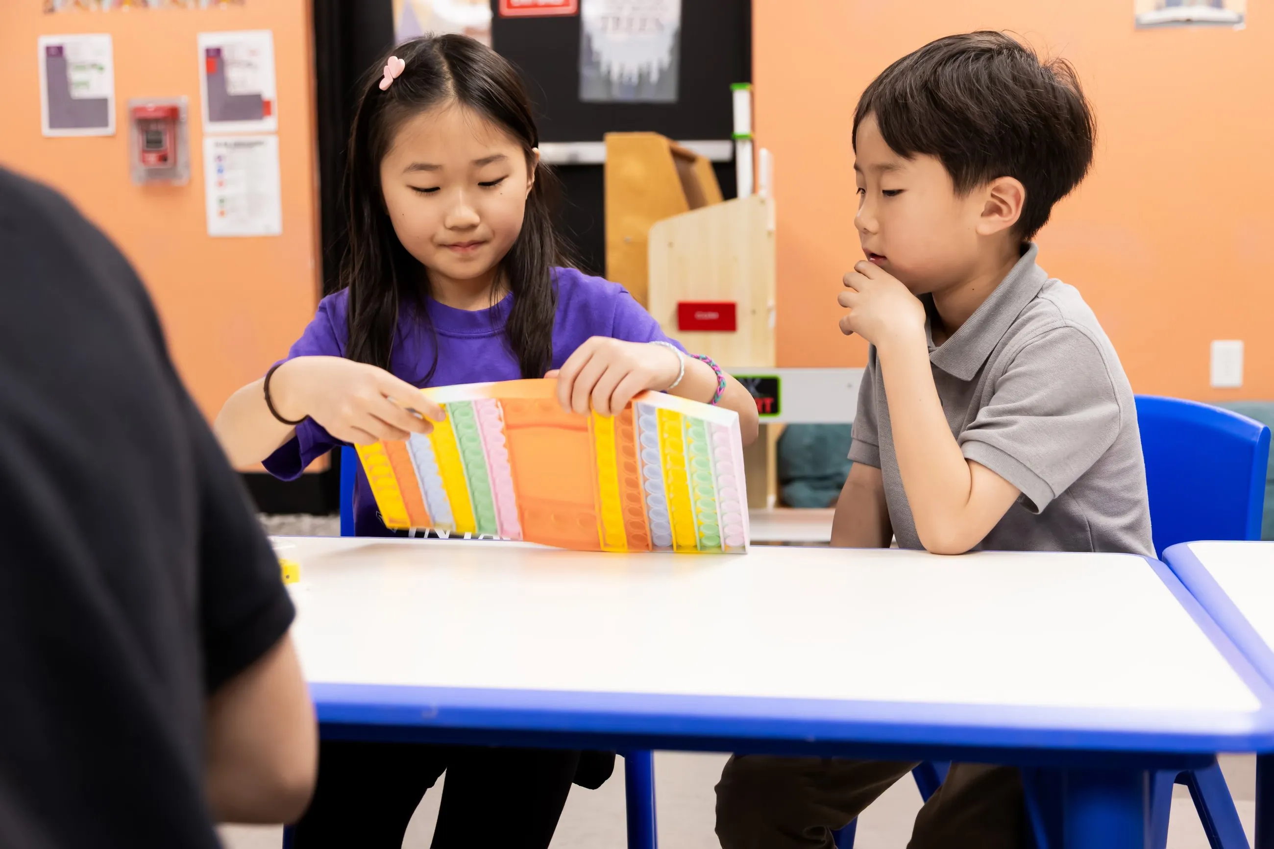 Two students collaborate on a colorful hands-on classroom project.